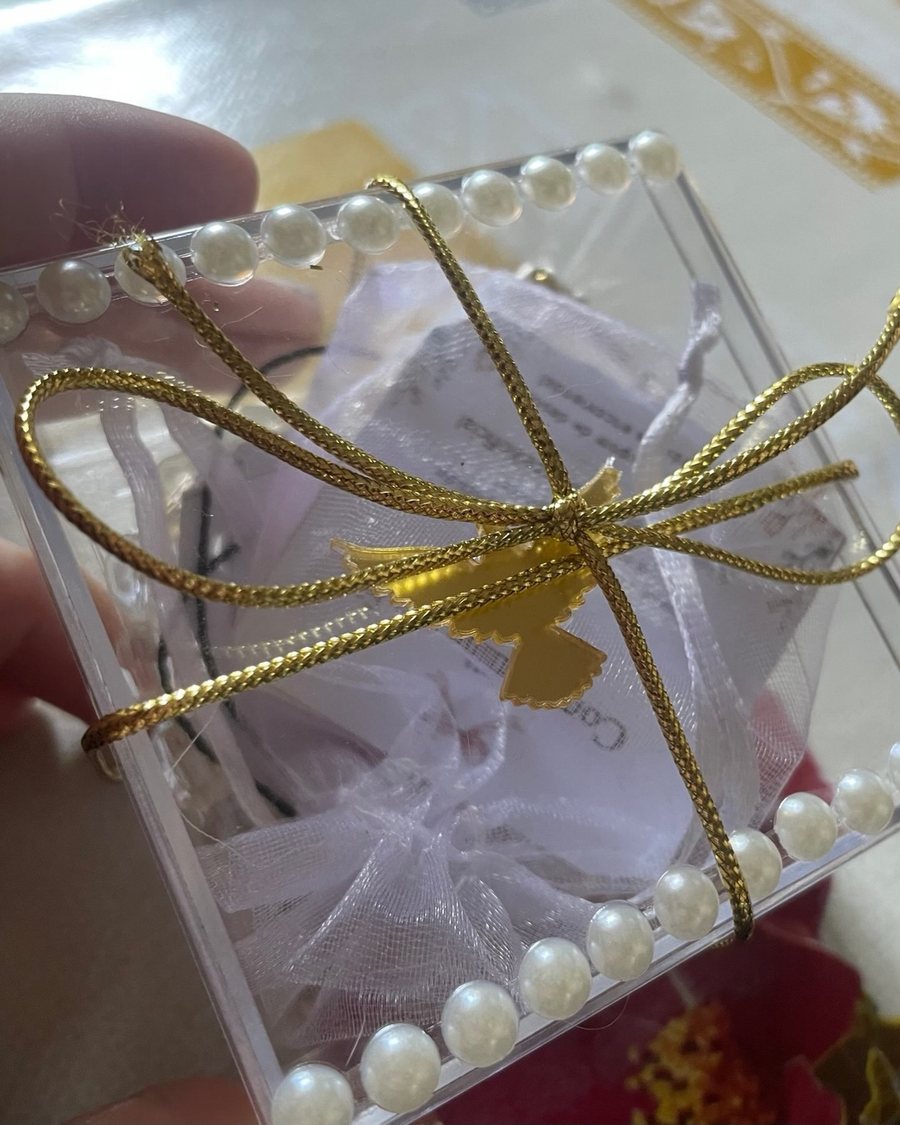 Caixinha de acrílico com pérolas e laço dourado usada na entrega